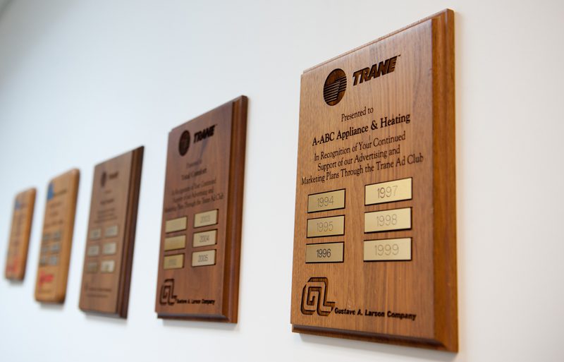 Line of award plaques for Total Comfort, an HVAC company in Minneapolis, hanging on an office wall.