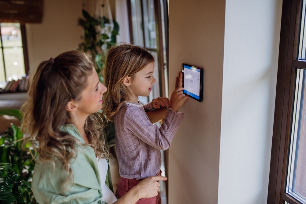 Mother and daughter adjusting thermostat settings